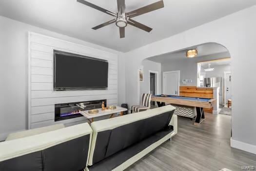 living room featuring a fireplace, ceiling fan, hardwood / wood-style floors, and pool table