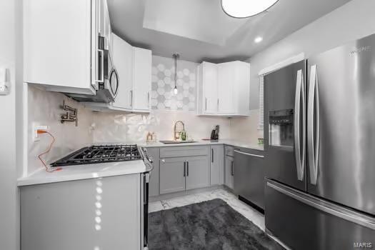 kitchen featuring tasteful backsplash, stainless steel appliances, sink, gray cabinets, and white cabinetry