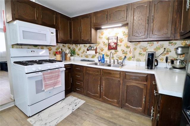 kitchen featuring white appliances, light hardwood / wood-style flooring, dark brown cabinets, and sink