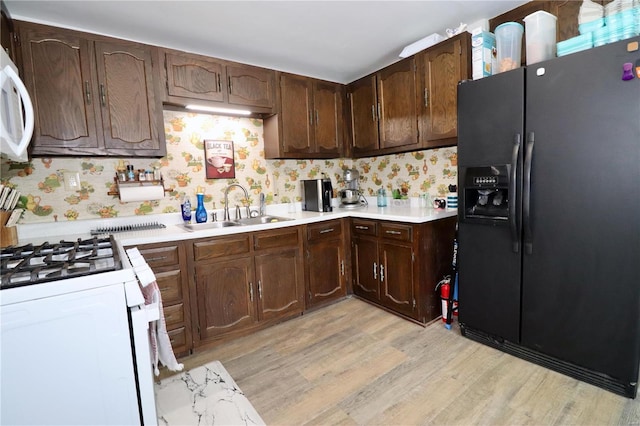 kitchen with white appliances, light hardwood / wood-style flooring, backsplash, dark brown cabinets, and sink