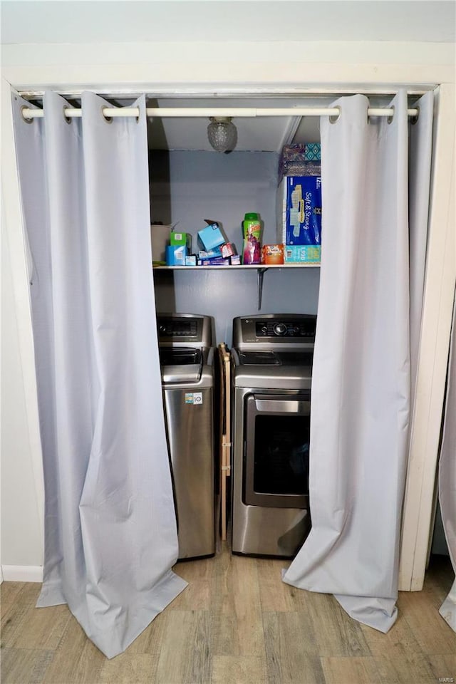 laundry room with separate washer and dryer and light hardwood / wood-style flooring