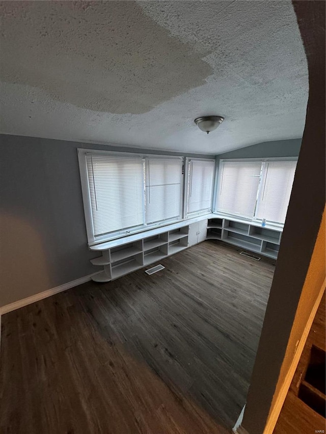 unfurnished room with lofted ceiling, dark hardwood / wood-style flooring, and a textured ceiling