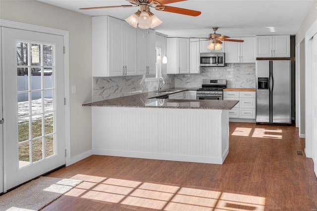 kitchen featuring stainless steel appliances, white cabinetry, and kitchen peninsula