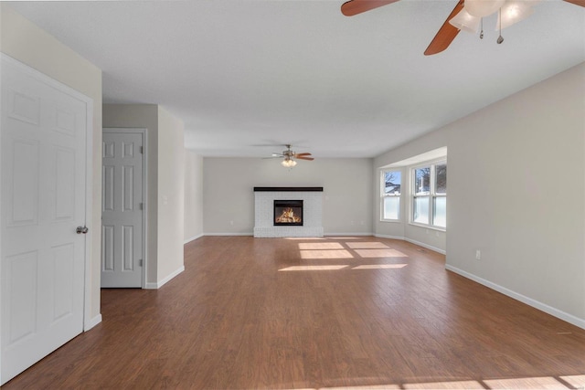 unfurnished living room featuring a fireplace, dark wood-type flooring, and ceiling fan