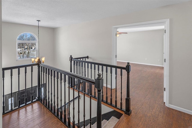 stairway featuring hardwood / wood-style flooring, an inviting chandelier, and a textured ceiling