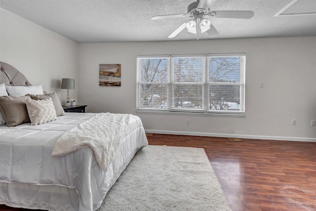 bedroom featuring dark hardwood / wood-style flooring, a textured ceiling, and ceiling fan