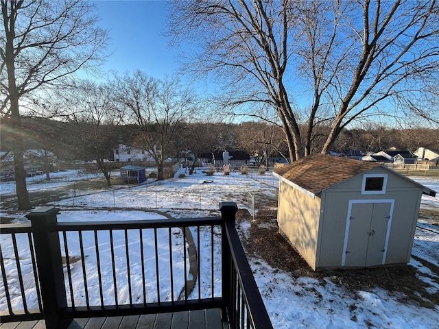 yard covered in snow featuring a wooden deck and a storage shed