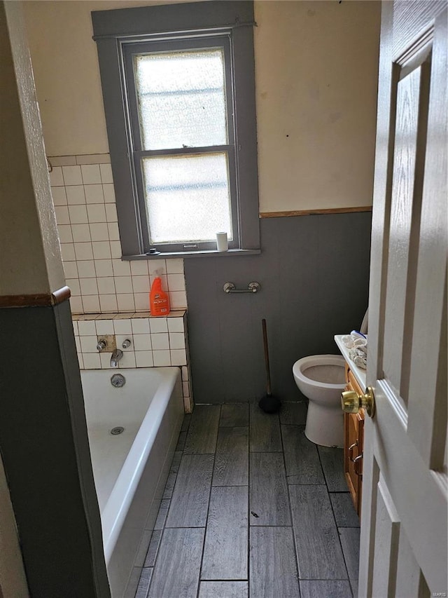 bathroom featuring vanity, a washtub, and toilet