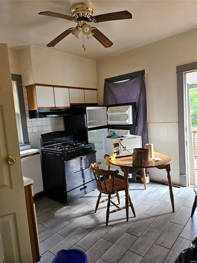 kitchen featuring black gas range oven, ceiling fan, white cabinets, and decorative backsplash