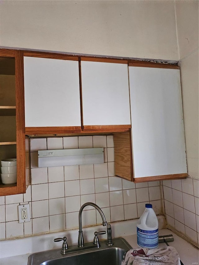 details featuring sink, decorative backsplash, and white cabinetry