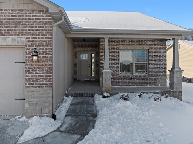 snow covered property entrance with a garage