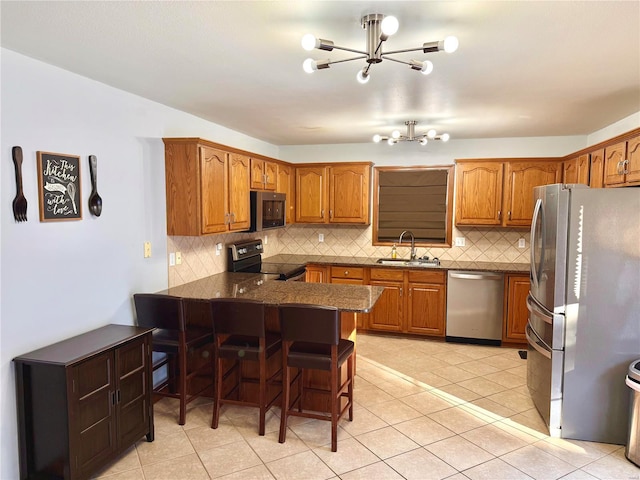 kitchen with an inviting chandelier, kitchen peninsula, stainless steel appliances, a kitchen breakfast bar, and sink