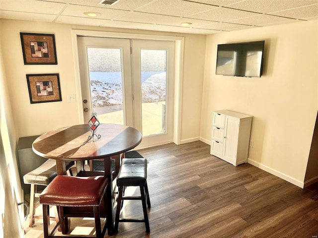 dining space featuring a paneled ceiling and dark hardwood / wood-style flooring