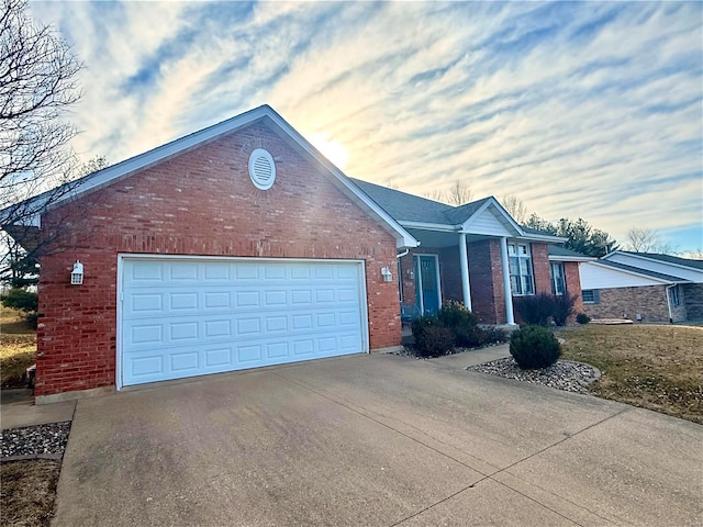 single story home featuring driveway, a garage, and brick siding