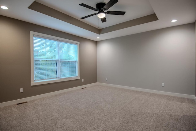 carpeted empty room with ceiling fan and a tray ceiling