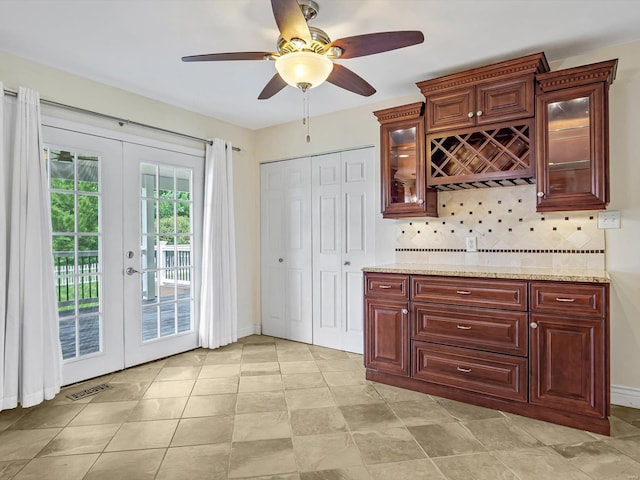 kitchen featuring light stone countertops, ceiling fan, french doors, and backsplash