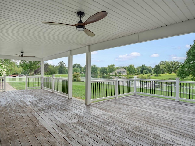 deck with ceiling fan, a yard, and a water view