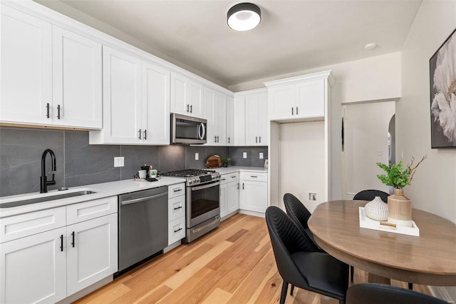 kitchen featuring stainless steel appliances, decorative backsplash, white cabinetry, and sink