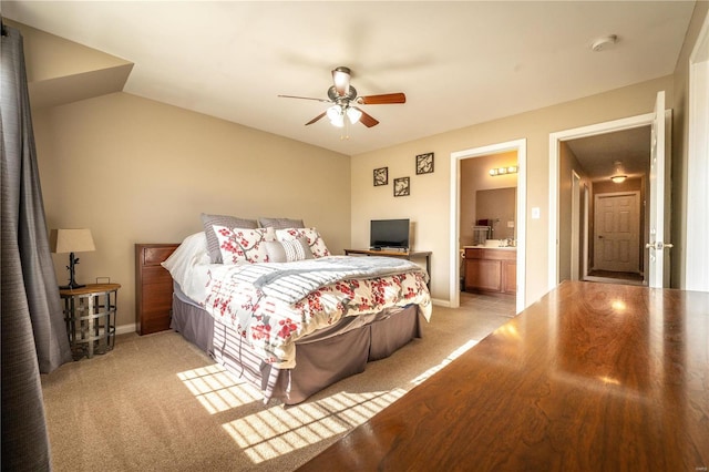 bedroom with ensuite bath, light carpet, and ceiling fan