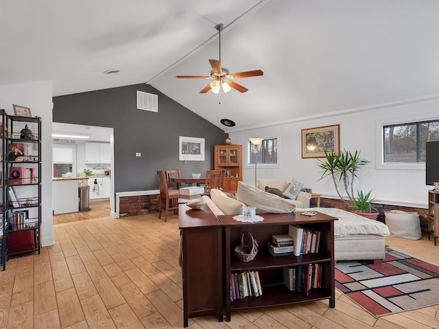 living room featuring lofted ceiling, a ceiling fan, visible vents, and light wood-style floors