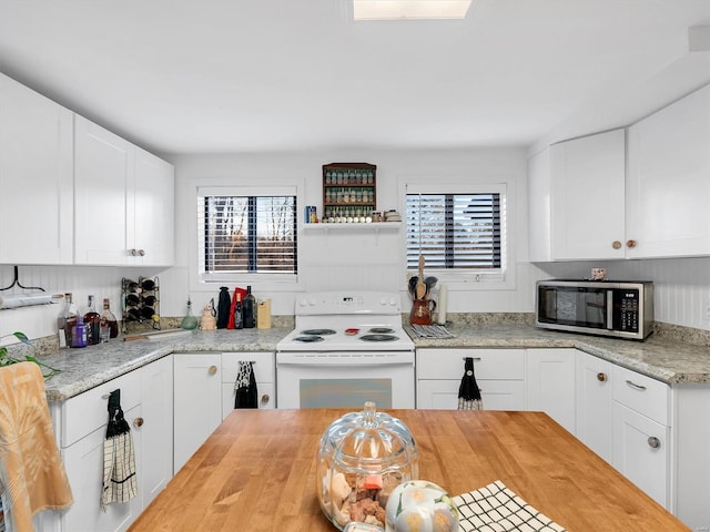 kitchen with butcher block countertops, stainless steel microwave, white electric range oven, and white cabinets