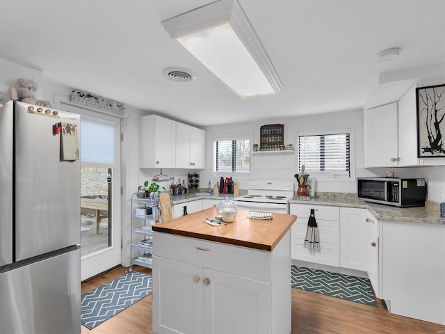 kitchen with visible vents, butcher block counters, appliances with stainless steel finishes, wood finished floors, and white cabinetry