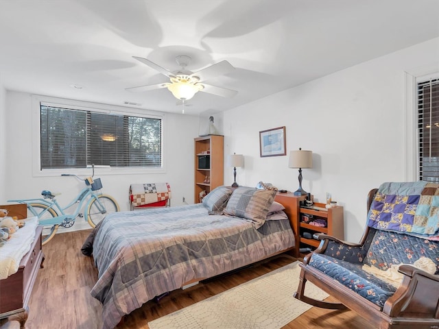 bedroom with visible vents, wood finished floors, and a ceiling fan