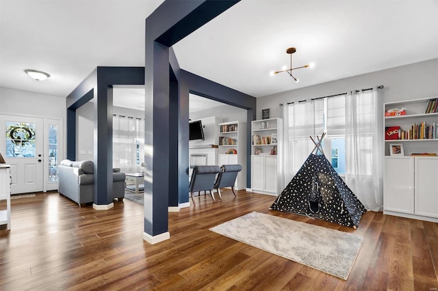 game room with dark wood-type flooring and a chandelier