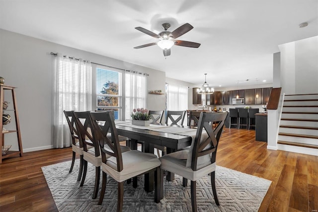 dining room featuring sink, ceiling fan with notable chandelier, and dark wood-type flooring