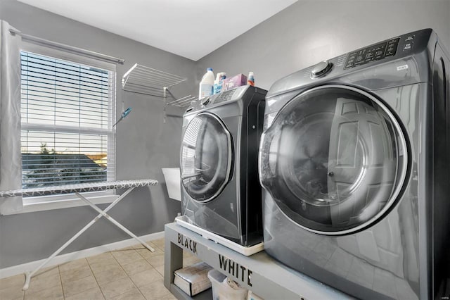 clothes washing area featuring light tile patterned floors and washing machine and clothes dryer