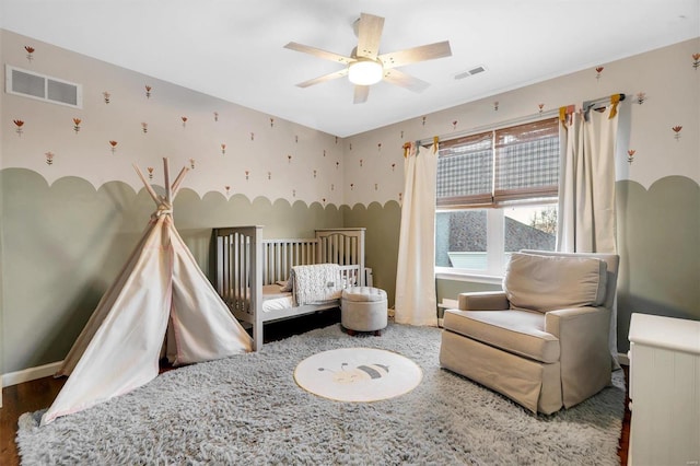 bedroom featuring hardwood / wood-style flooring, a nursery area, and ceiling fan