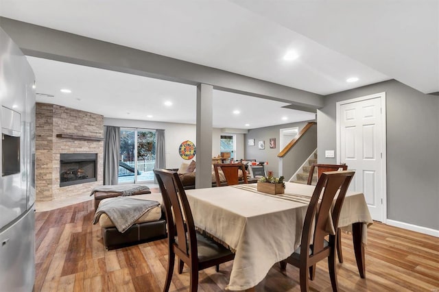 dining room with a stone fireplace and light wood-type flooring