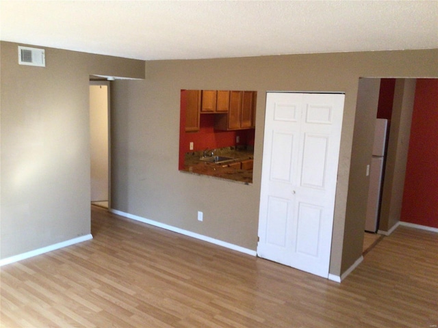 unfurnished room with sink and light hardwood / wood-style floors