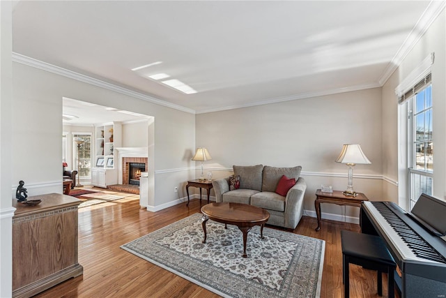 living room featuring built in features, a brick fireplace, crown molding, and wood-type flooring