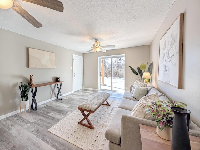 living room featuring ceiling fan, light hardwood / wood-style floors, and a textured ceiling