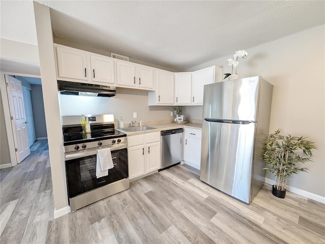 kitchen with appliances with stainless steel finishes, sink, white cabinets, a textured ceiling, and light hardwood / wood-style flooring