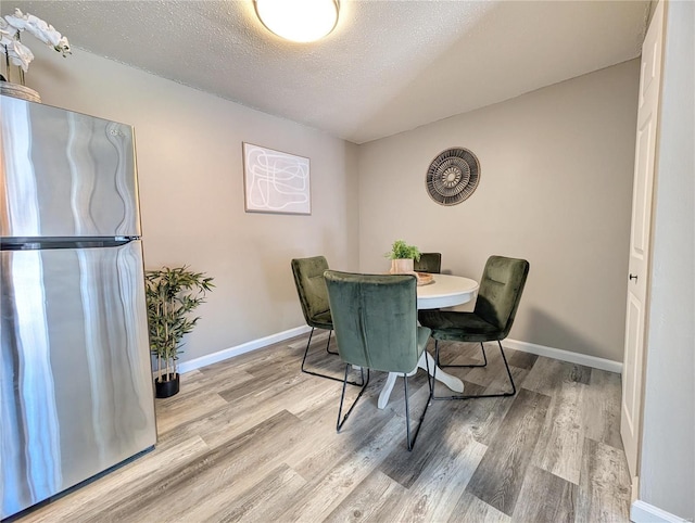 dining space featuring wood-type flooring and a textured ceiling