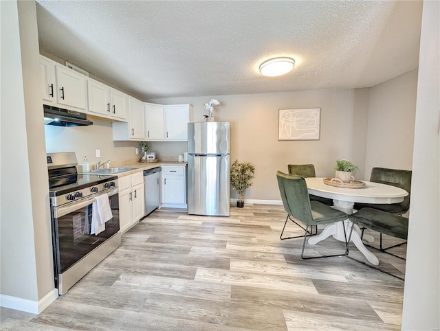 kitchen with stainless steel appliances, a textured ceiling, light hardwood / wood-style flooring, and white cabinets