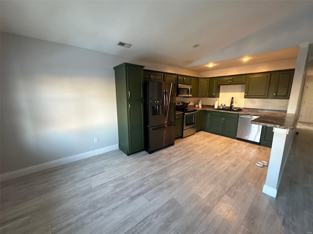 kitchen with lofted ceiling, stainless steel appliances, light wood-type flooring, and sink