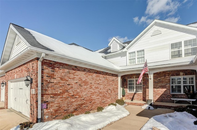 view of snowy exterior featuring a garage