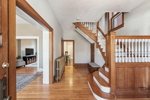 interior space with stairs, radiator, light wood-style floors, and baseboards