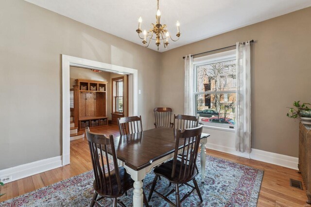 dining space featuring visible vents, an inviting chandelier, baseboards, and light wood-style floors