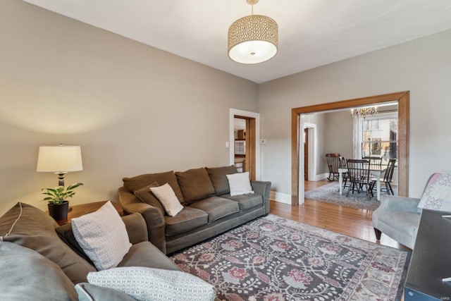 living room featuring an inviting chandelier, wood finished floors, and baseboards