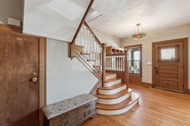 entryway featuring stairway, visible vents, baseboards, and light wood finished floors