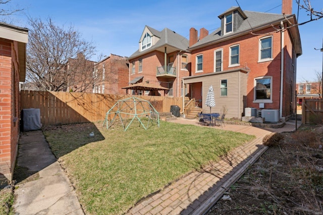 rear view of property featuring central AC unit, a playground, a fenced backyard, and brick siding