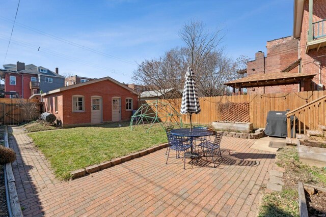 view of patio featuring an outbuilding, area for grilling, a fenced backyard, and outdoor dining space