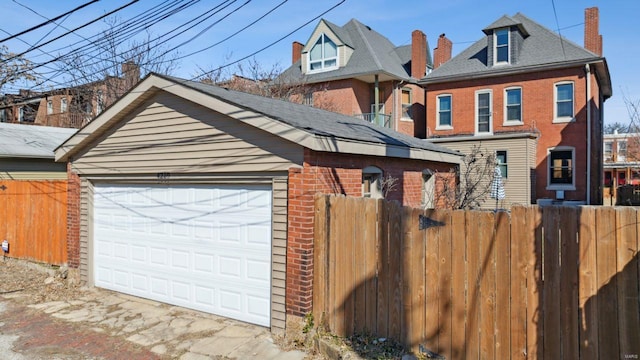 view of front of home featuring a detached garage, fence, and brick siding