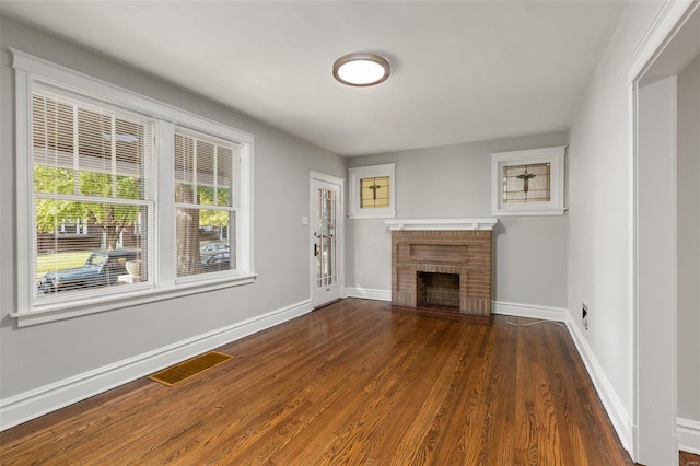 unfurnished living room featuring a brick fireplace and dark hardwood / wood-style floors