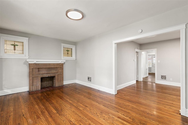 unfurnished living room featuring dark wood-type flooring and a brick fireplace