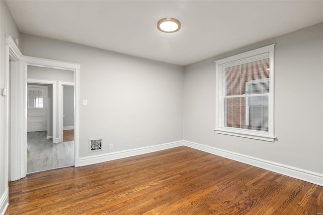 spare room with plenty of natural light and dark wood-type flooring